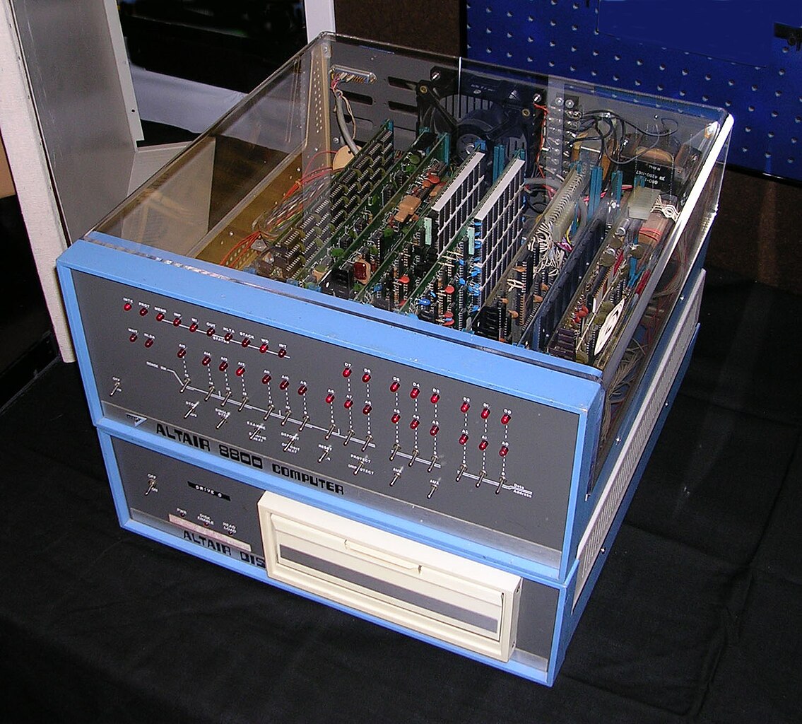 Ancien ordinateur Altair 8800 avec panneau de commandes et carte mère visible sous cloche transparente