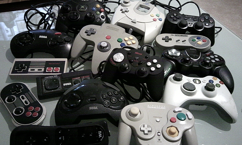 Collection variée de manettes de consoles de jeux rétro incluant Sega, Nintendo et autres modèles anciens